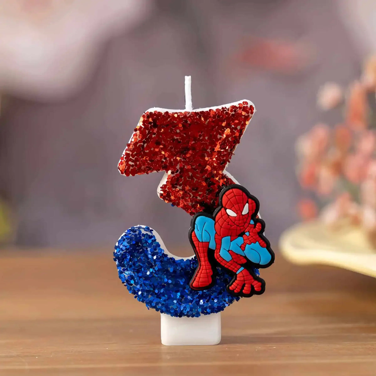 Number 3 birthday candle decorated with red and blue glitter and a cartoon superhero figure