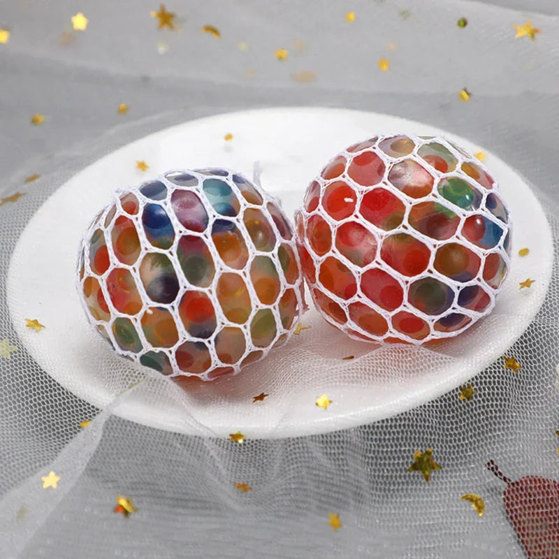 Two multi-coloured water bead stress balls on a white plate with star decoration