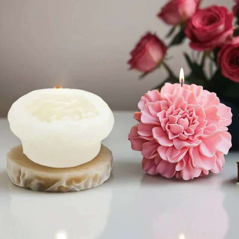 A lit pink peony candle next to a silicone mold base