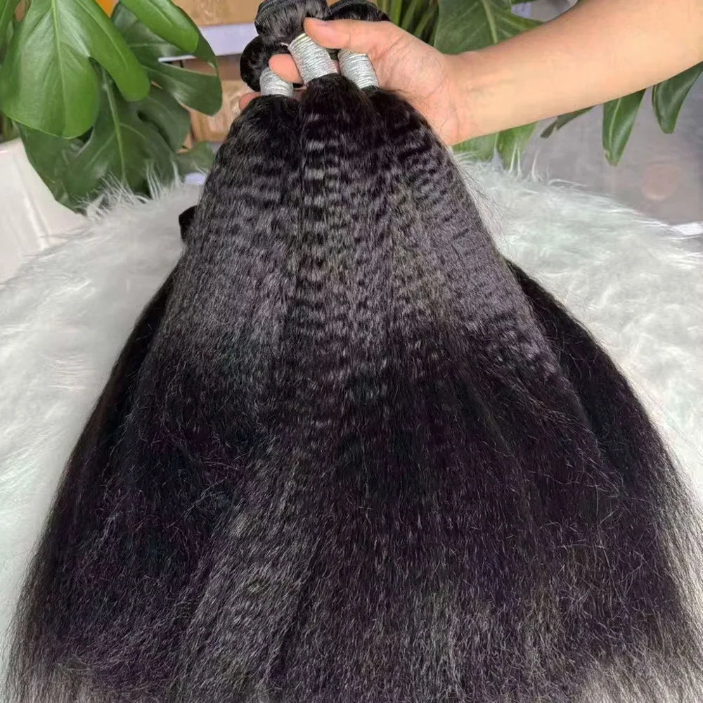 Close up of black kinky straight human hair extensions bundles held by a hand