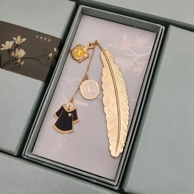 Golden metal feather bookmark with house crest charm and robe pendant in a box