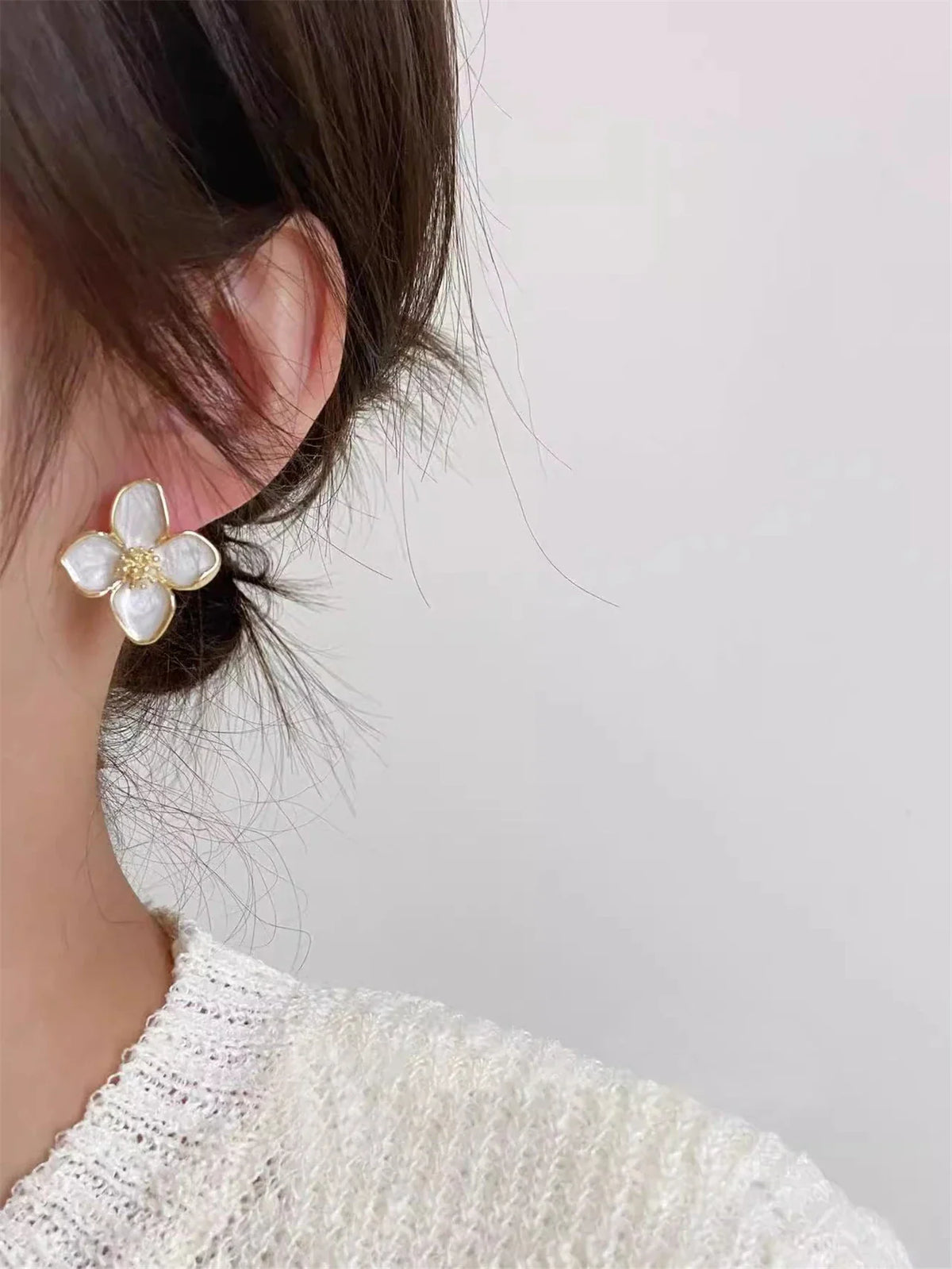 White floral stud earring worn on earlobe