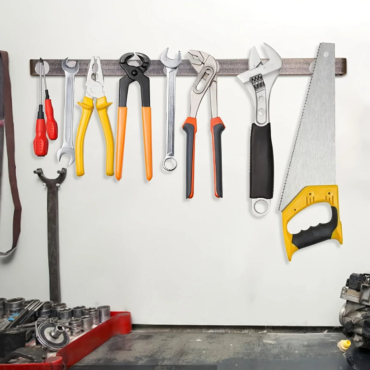 Various metal tools hanging from a magnetic strip on a white wall