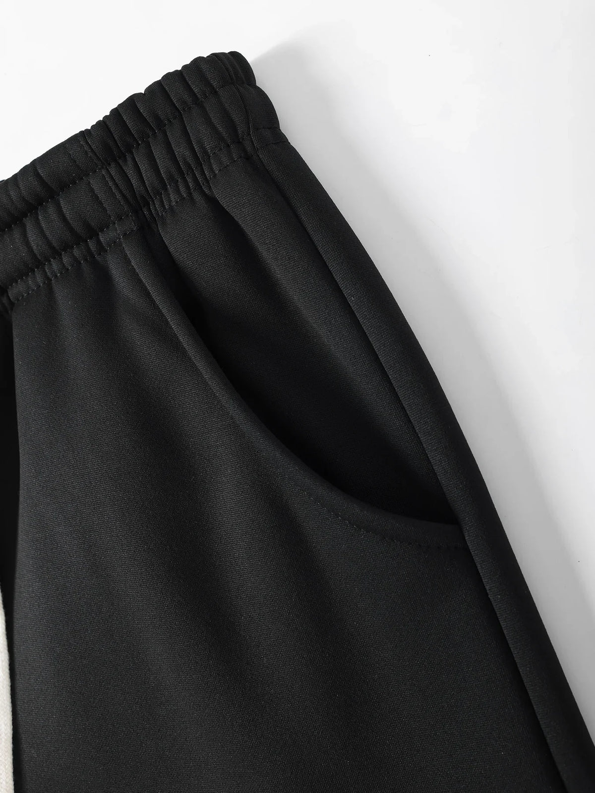 Close-up of black sports pants side pocket detail.