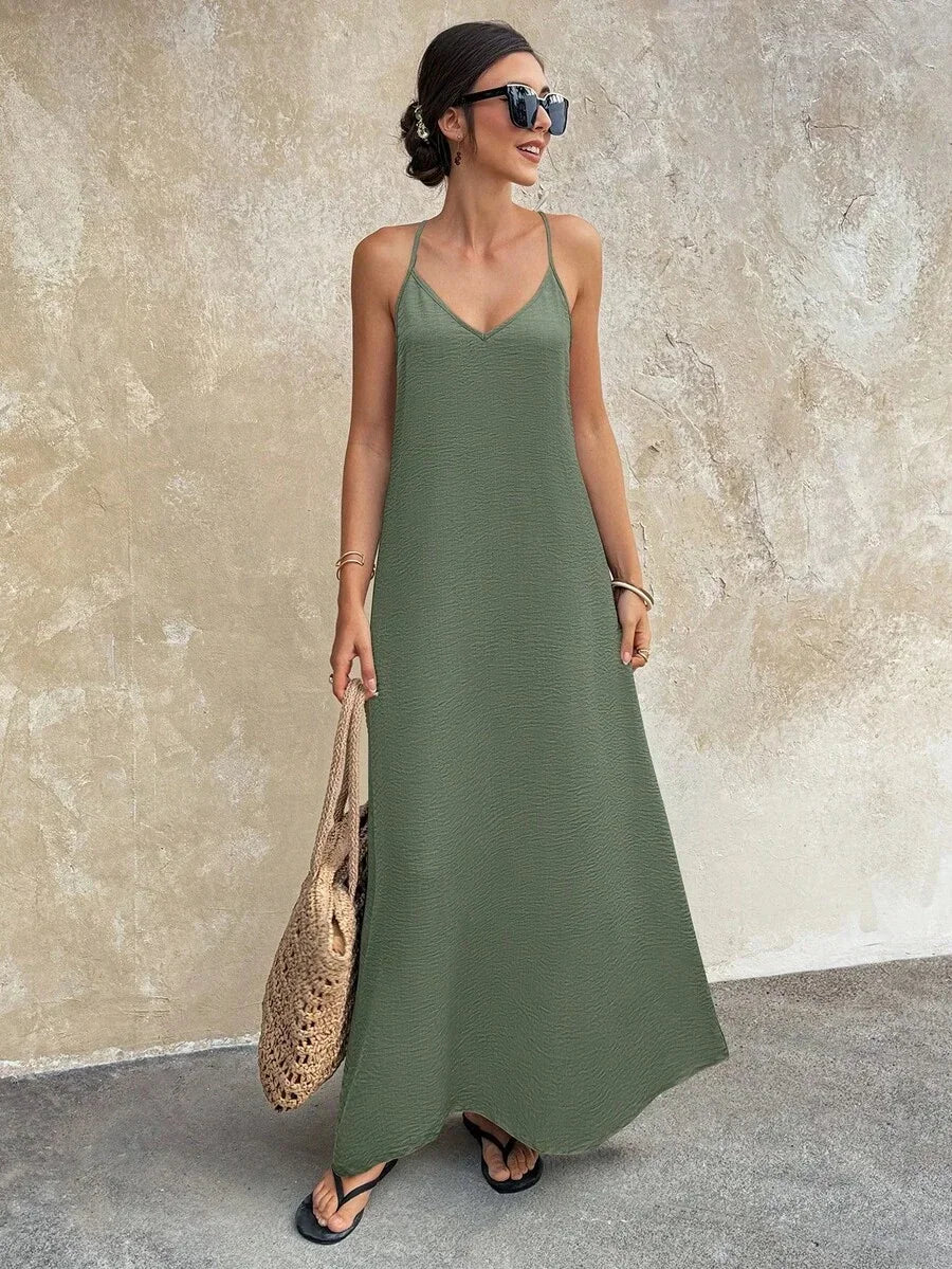 Woman in a khaki green sleeveless maxi dress with a v-neckline, holding a straw bag