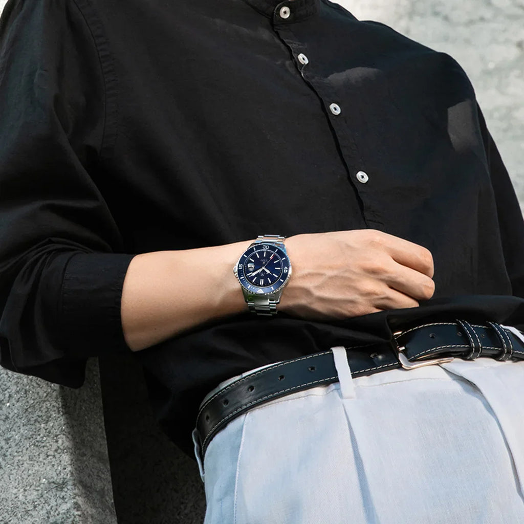 Person wearing a stainless steel automatic diver watch with a blue dial