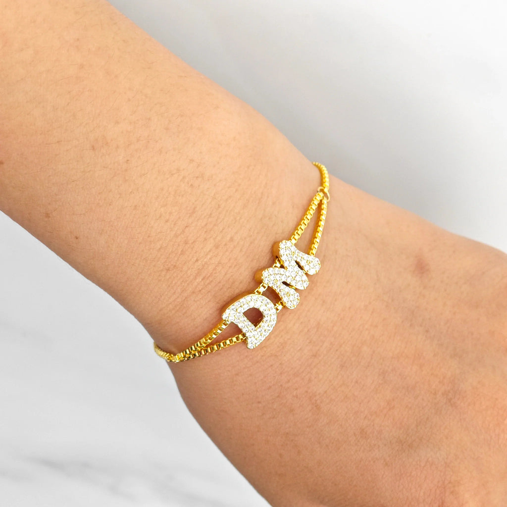 Custom gold-tone alphabet letter slider bracelet with double mesh chain worn on a wrist.