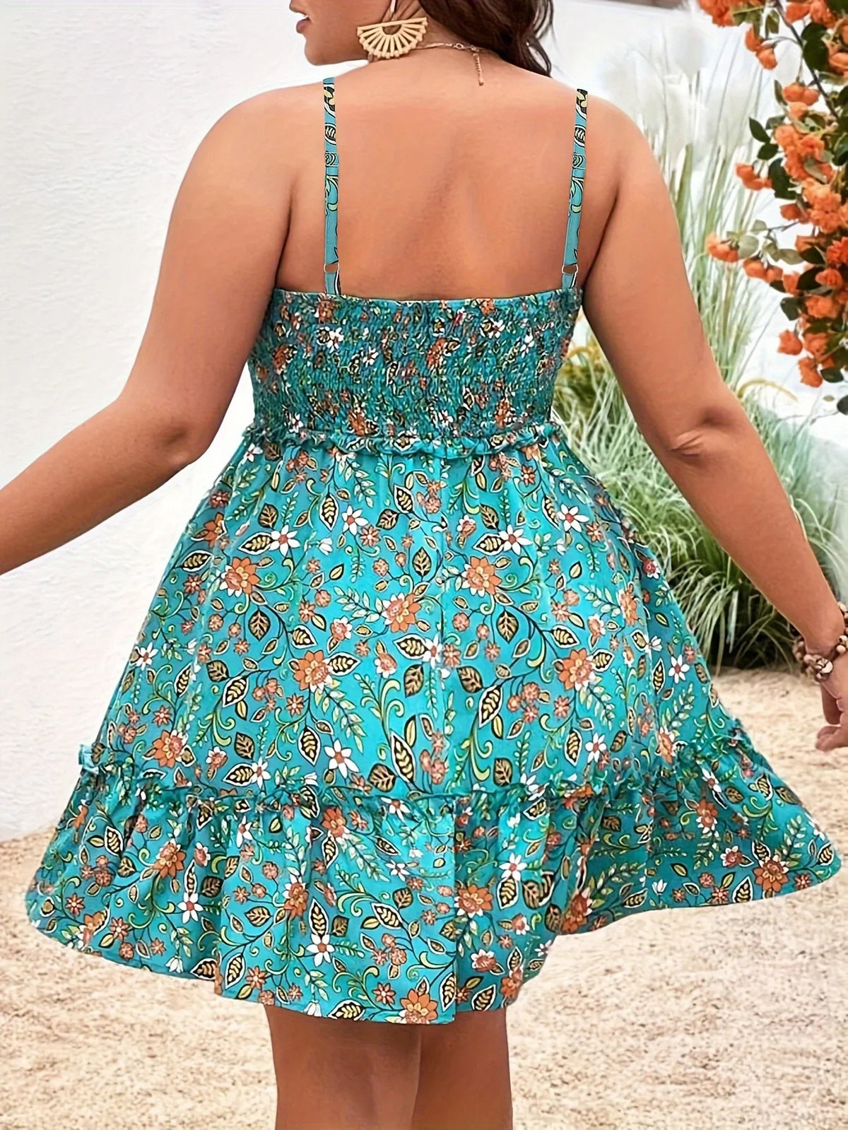 The back view of a turquoise floral print sleeveless dress with a gathered waist and ruffled hem.
