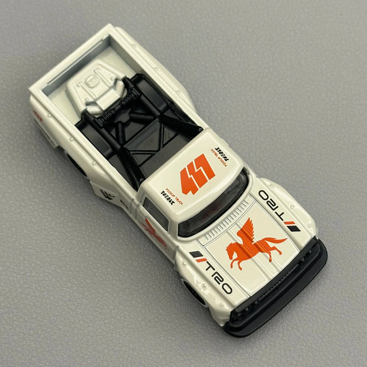 Top view of a white diecast pickup truck toy model with orange racing decals