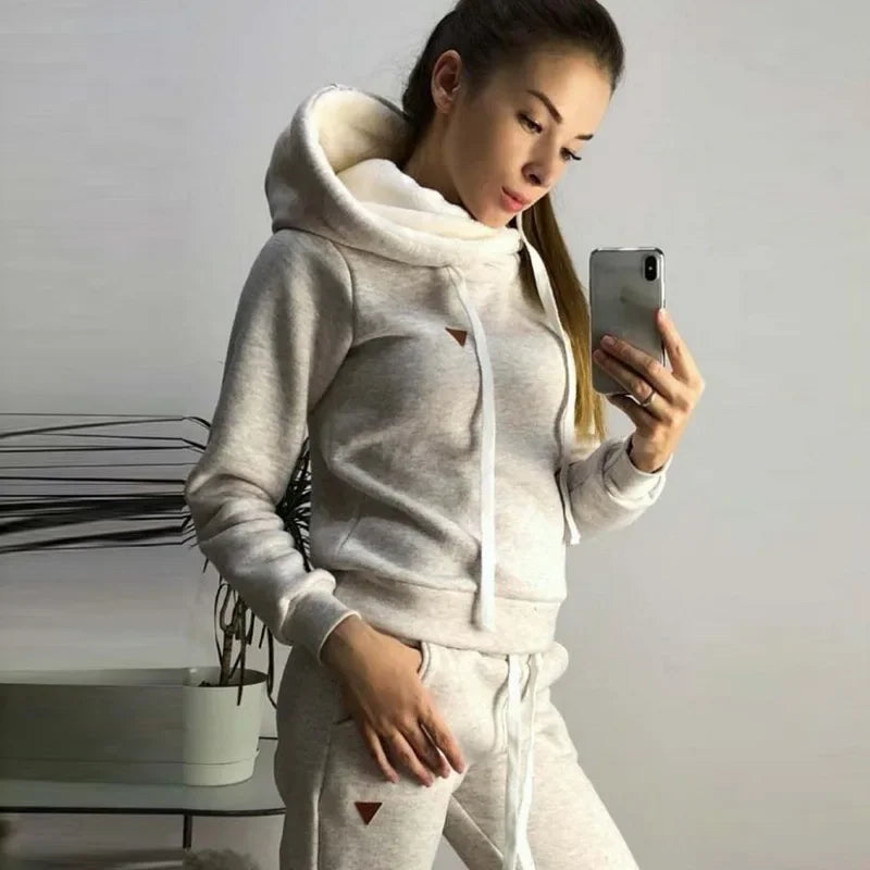 Close-up of a woman wearing a light gray fleece-lined hooded sweatshirt and matching sweatpants.