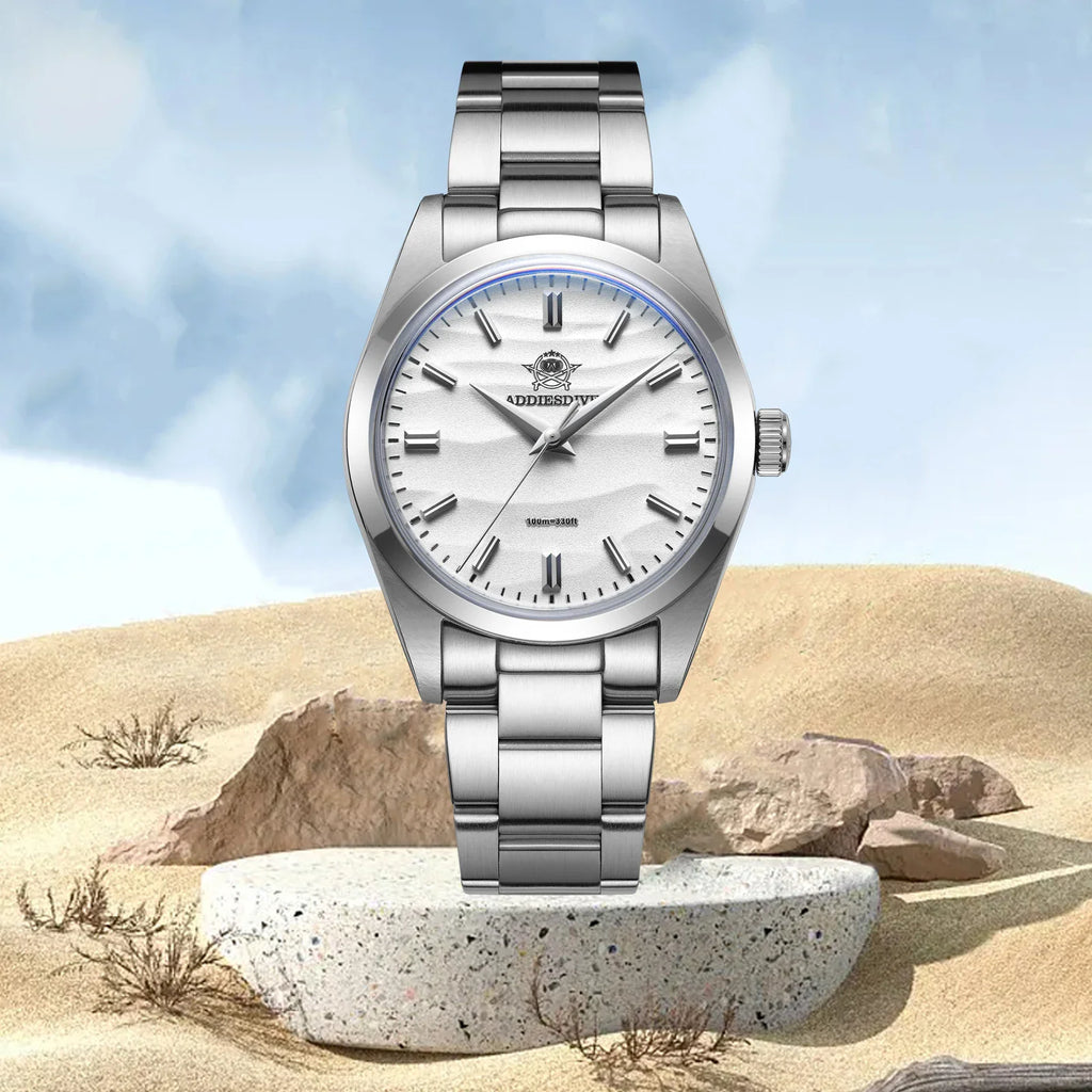 Stainless steel watch with a white dial displayed on a stone platform in a desert landscape