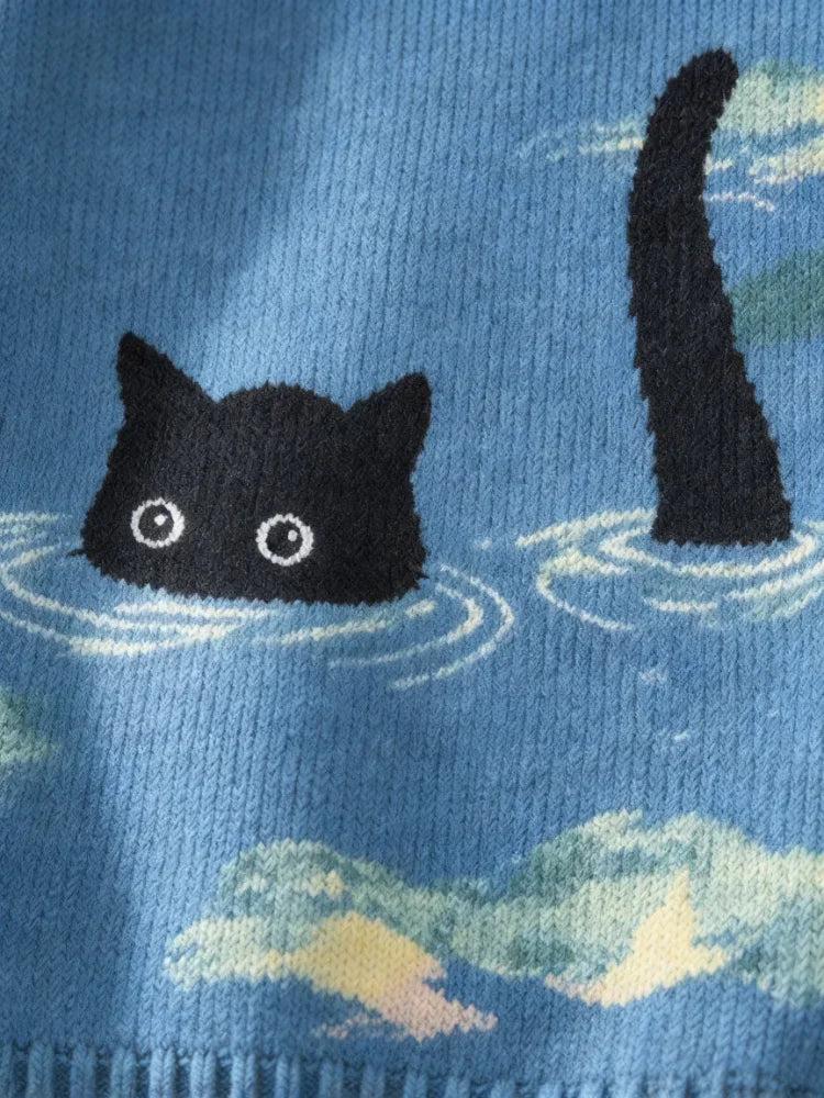 Close-up of the knitted graphic featuring a black cat head and tail in the water on a blue sweater