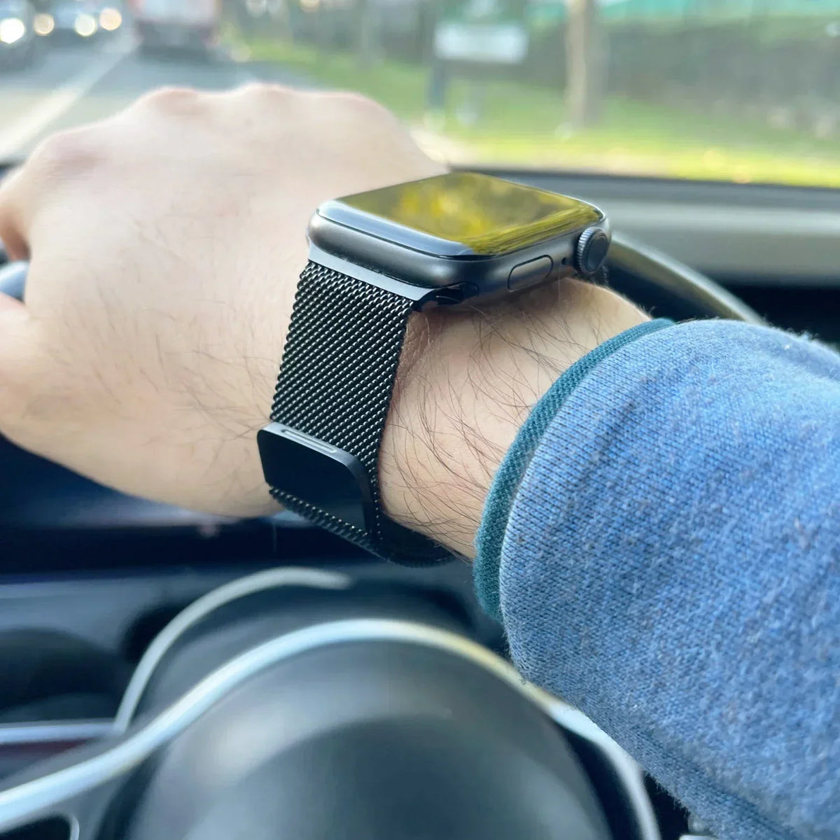 Black metal mesh watch band worn on a person's wrist while driving