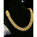 Men's heavy gold tone Cuban link chain necklace with sparkling moissanite stones on a black display bust