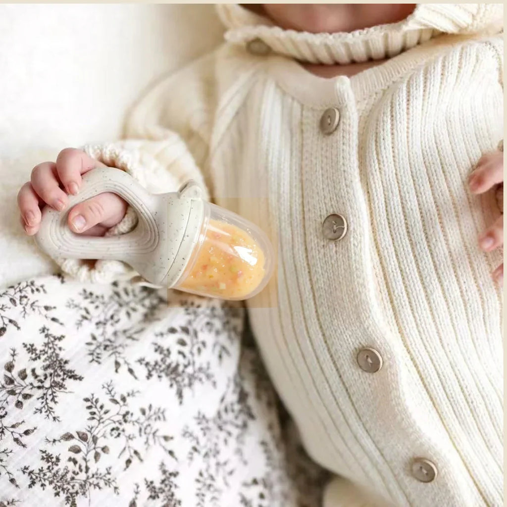 Baby holding a silicone fruit feeder teether pacifier