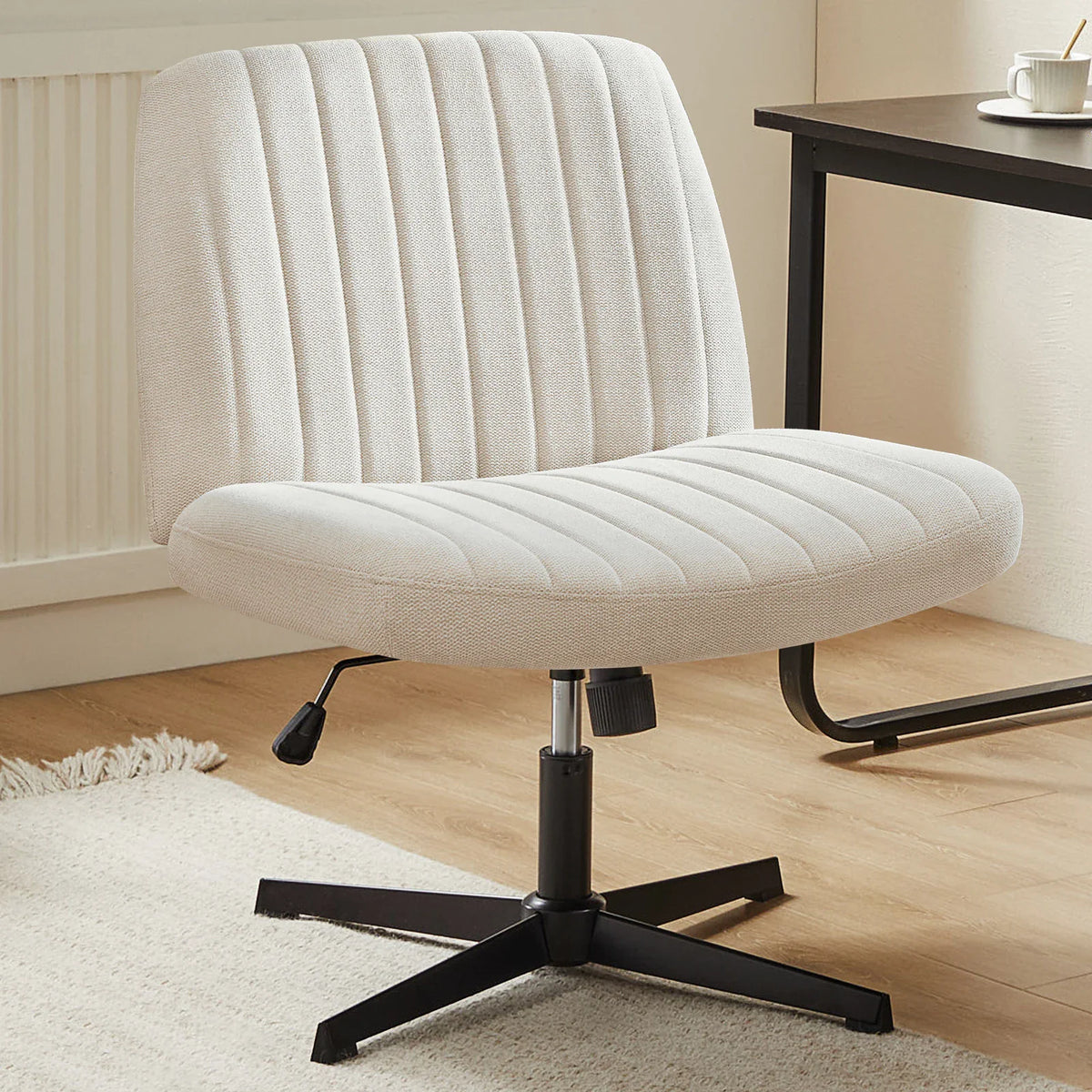 Beige upholstered armless swivel office chair with vertical tufting and black metal base