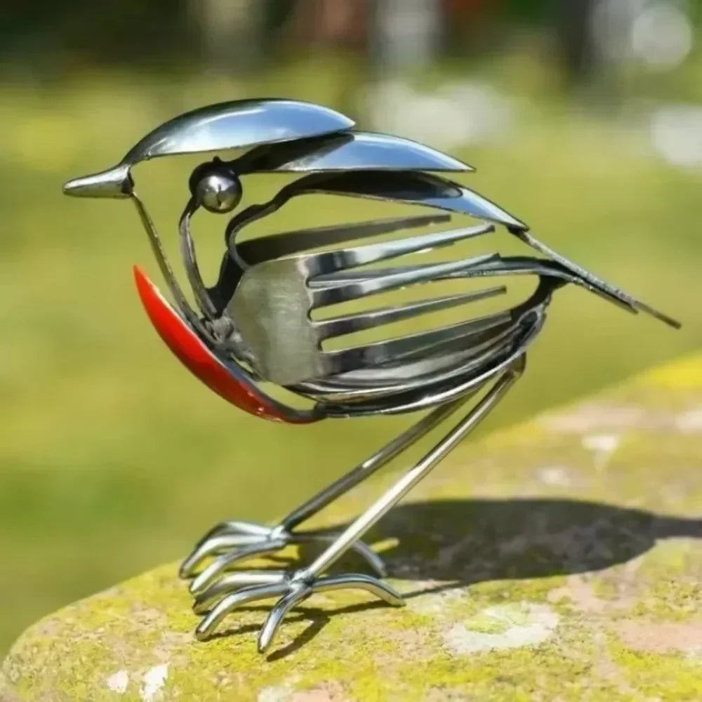 Stainless steel robin figurine made from cutlery standing on a weathered stone ledge