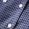 Close-up of blue and white plaid shirt with flower-shaped buttons