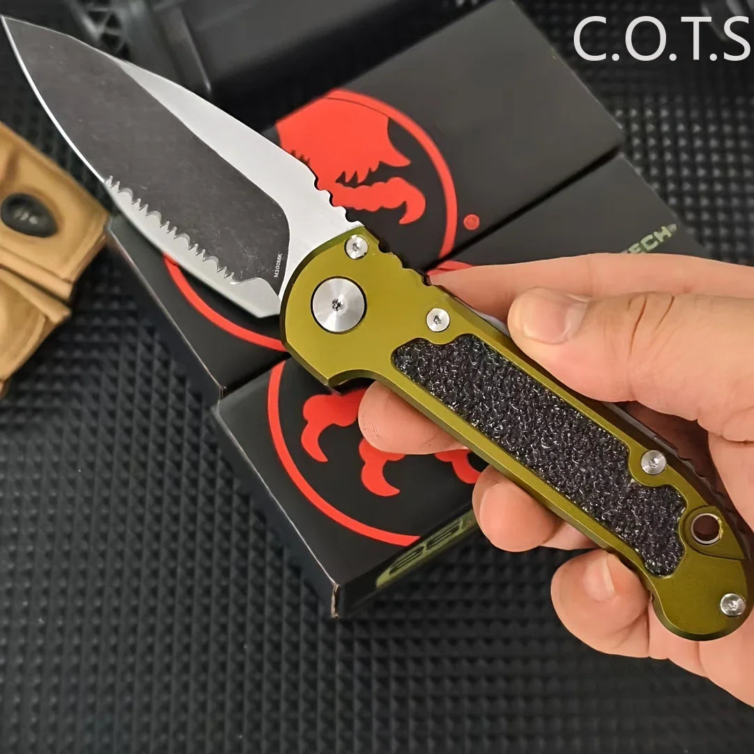 A hand holding a serrated folding pocket knife with an olive green handle and black textured grip.