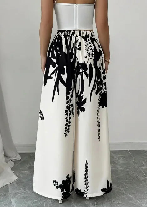 Back view of woman wearing black and white floral print wide leg trousers and white crop top