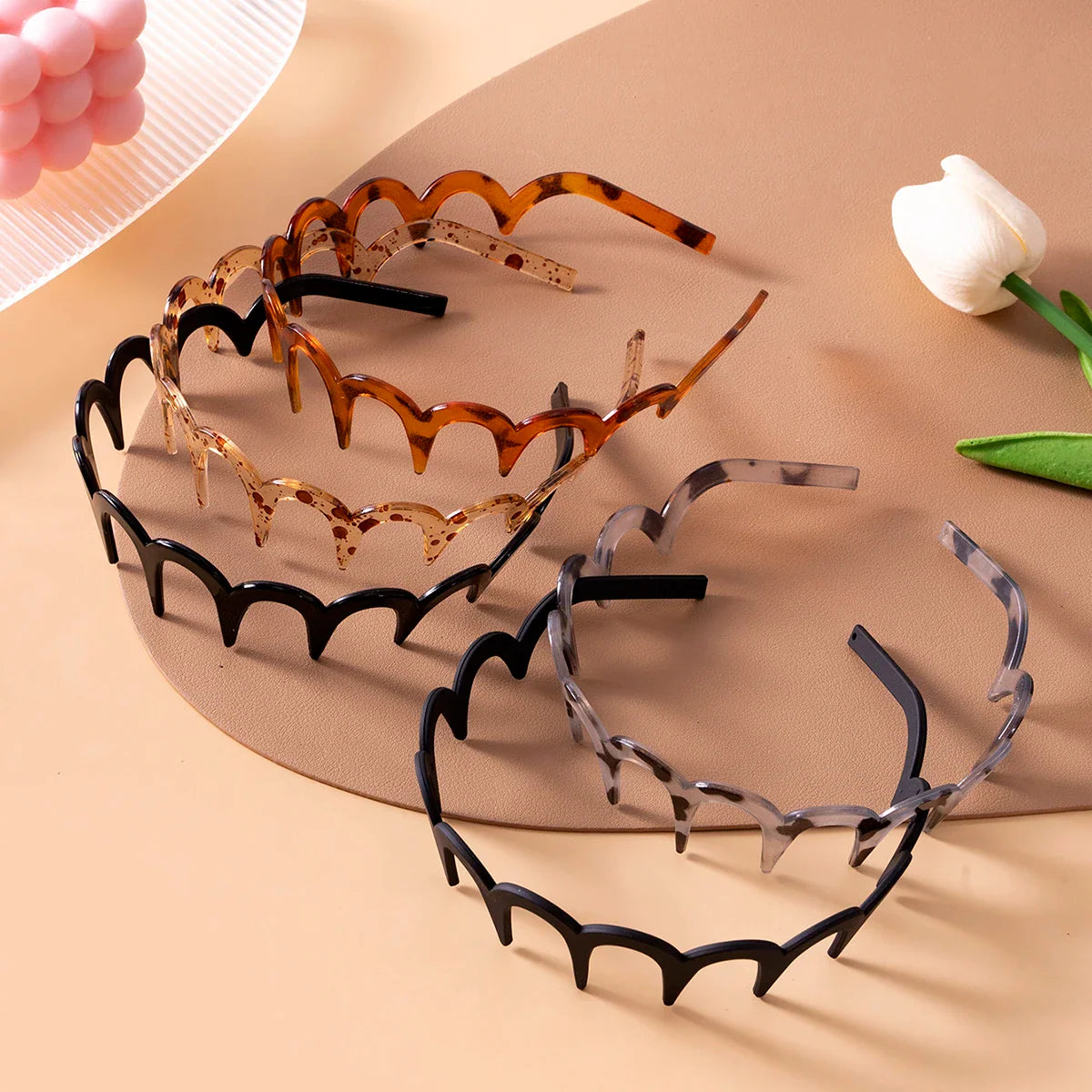 Several different colored scalloped plastic headbands displayed on a surface.