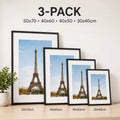A set of four black picture frames in descending sizes displayed on a wooden surface against a wall.