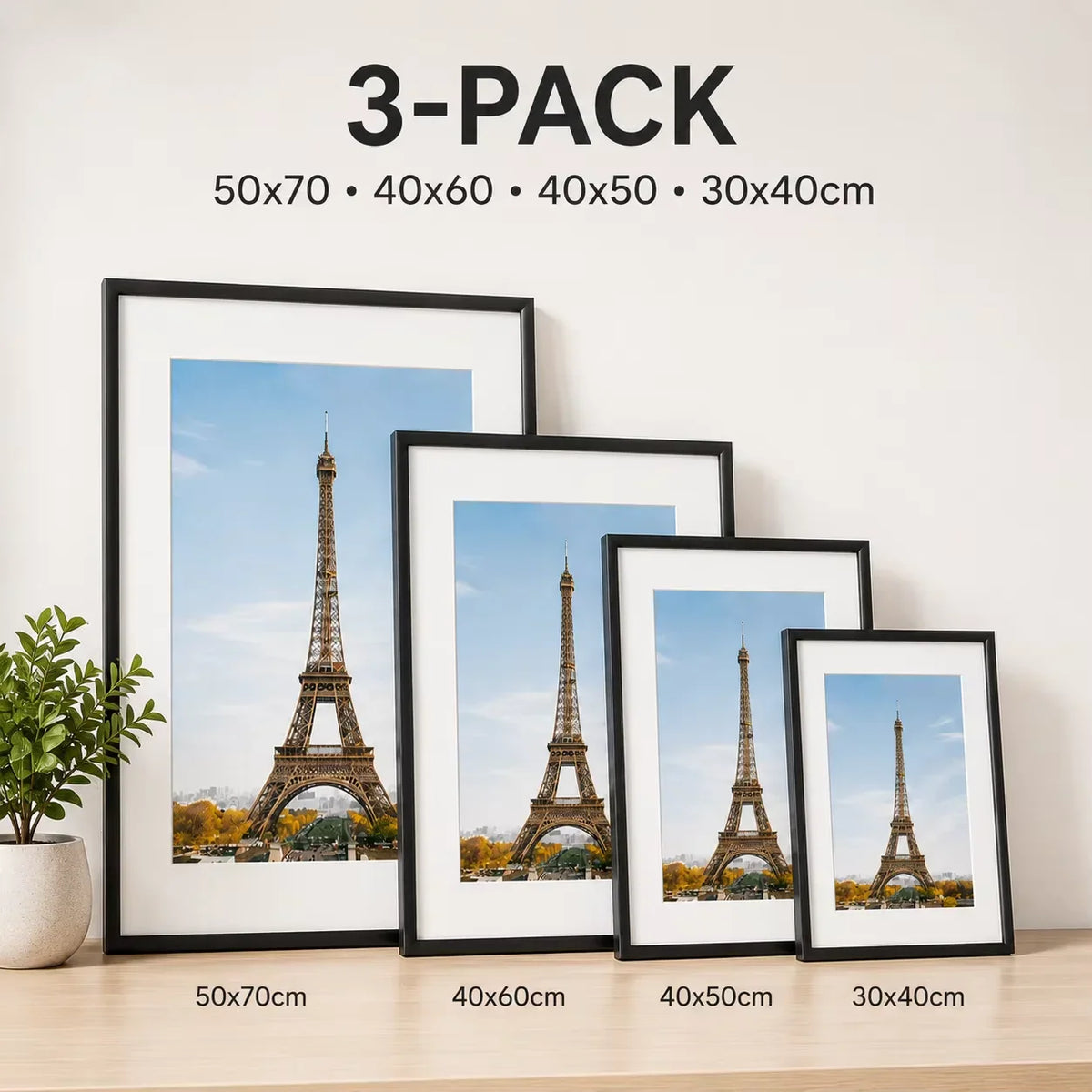 A set of four black picture frames in descending sizes displayed on a wooden surface against a wall.