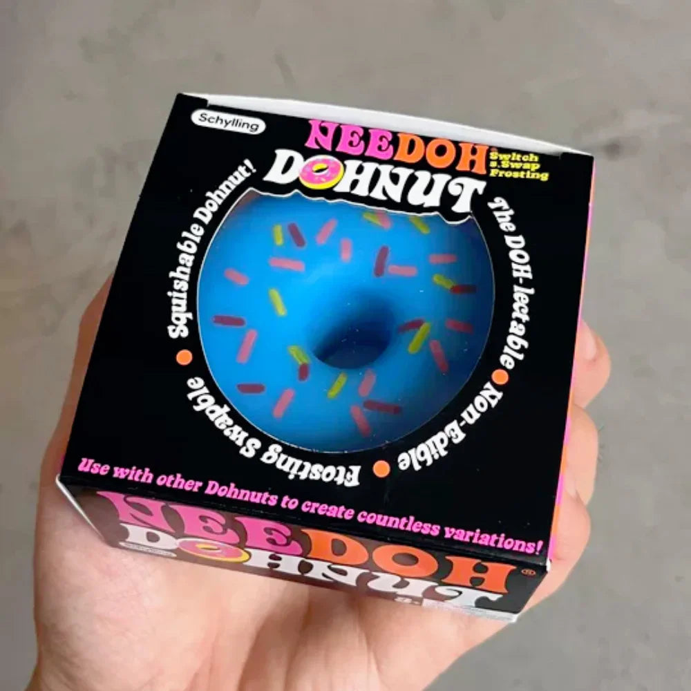 A hand holding a blue squishy donut toy inside its packaging box.
