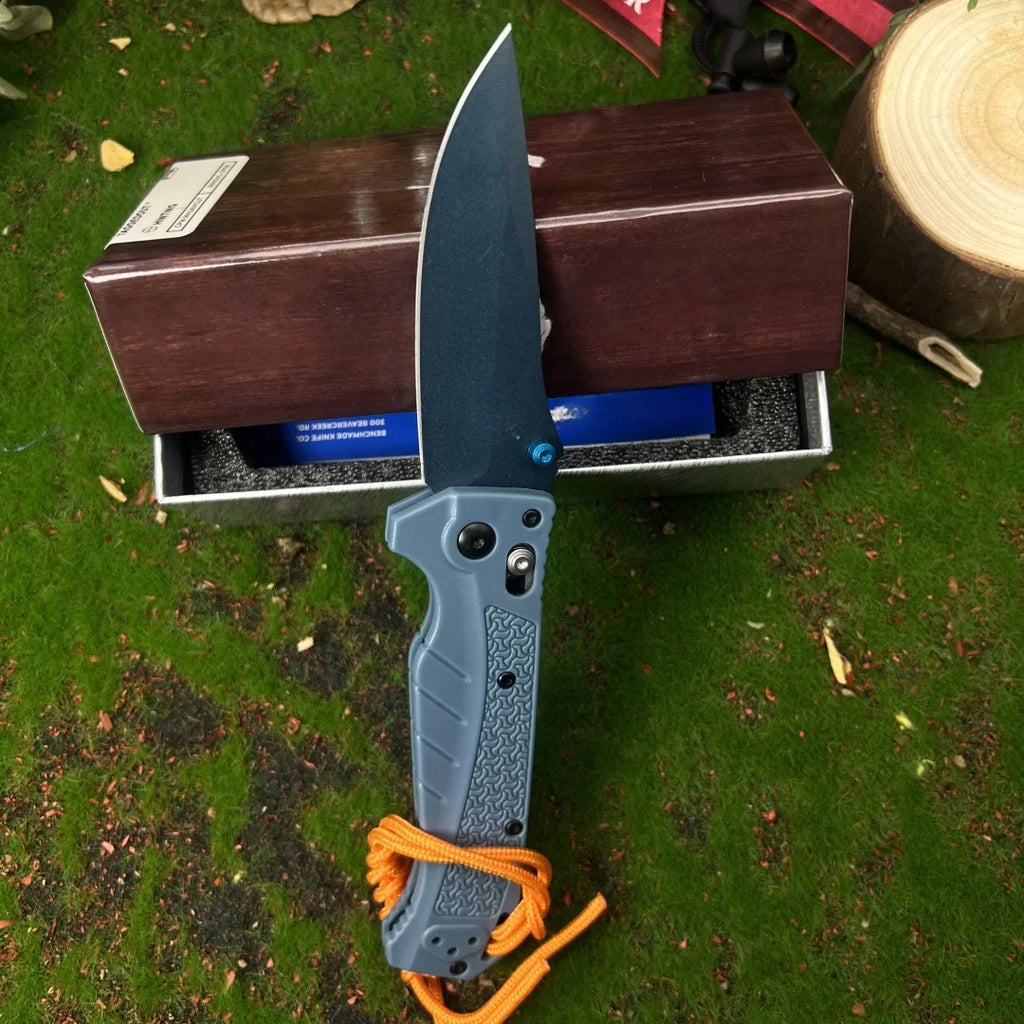 Grey folding pocket knife with a drop point blade and textured handle with an orange paracord lanyard