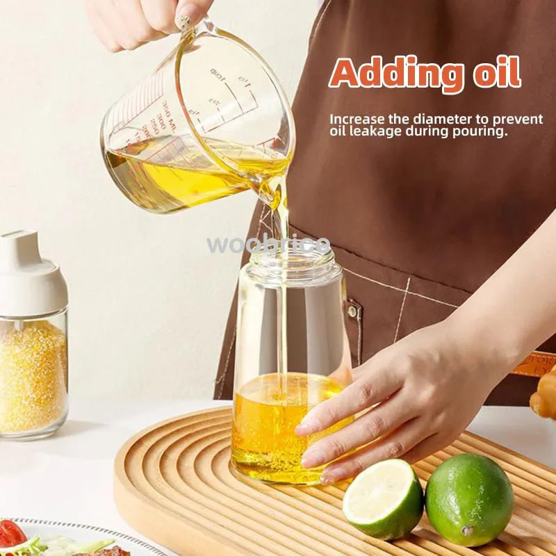 Hand pouring oil into a clear glass oil dispenser bottle