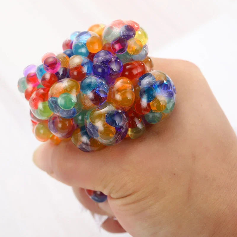 Hand squeezing a multi-coloured water bead stress ball