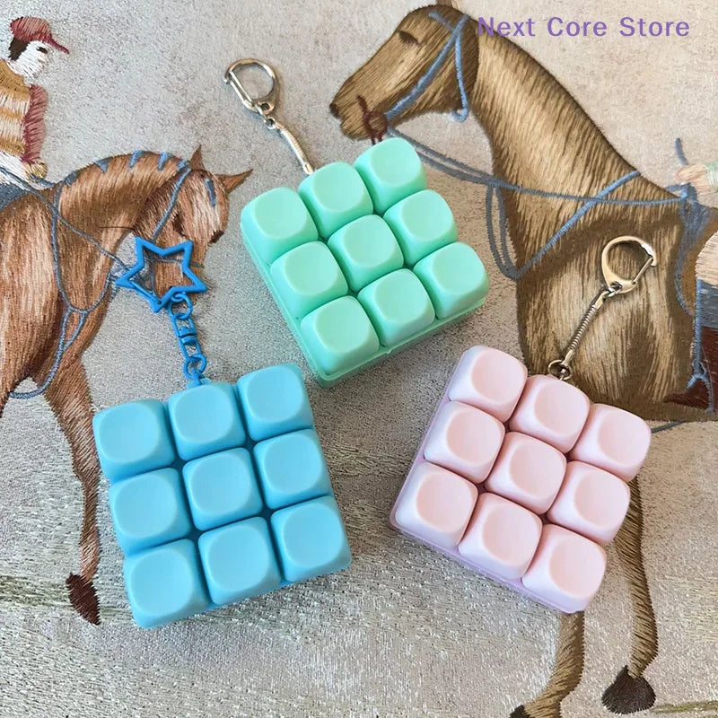 Three colorful 9-key keyboard fidget keychains resting on a fabric with horse motifs