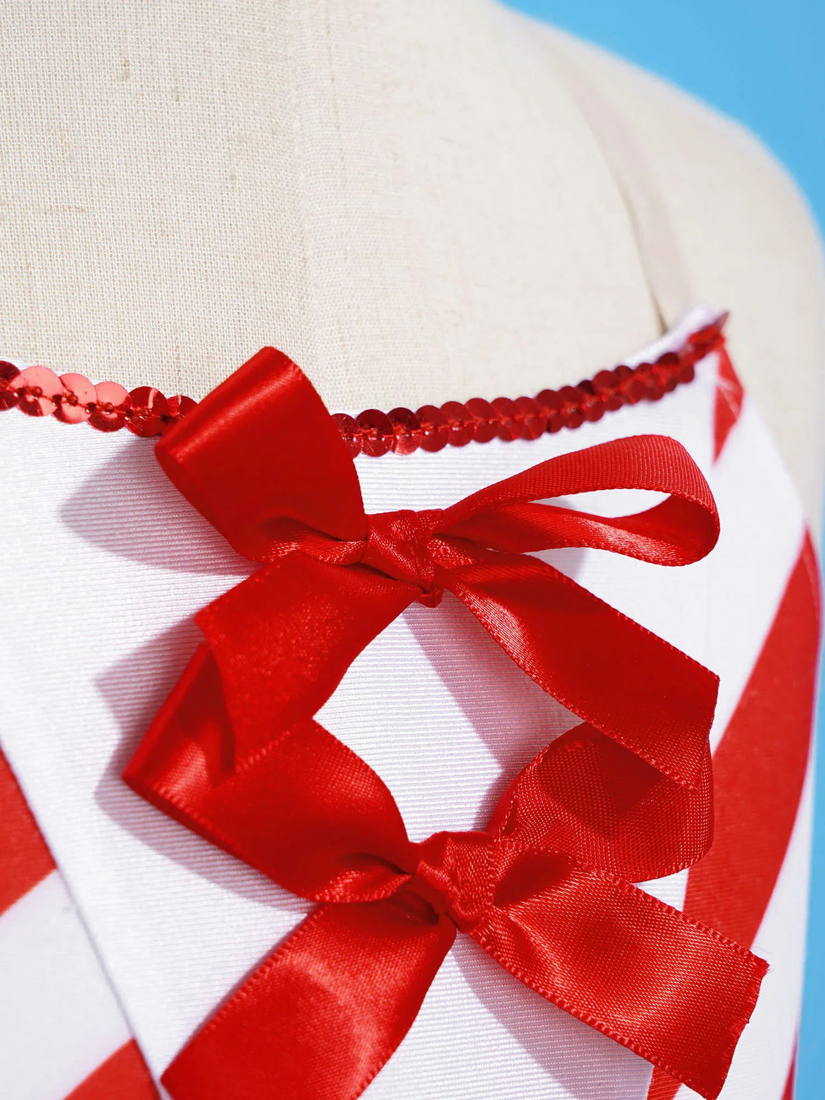 A close-up of the red ribbon lace-up detail on the candy cane striped ballet dress bodice.