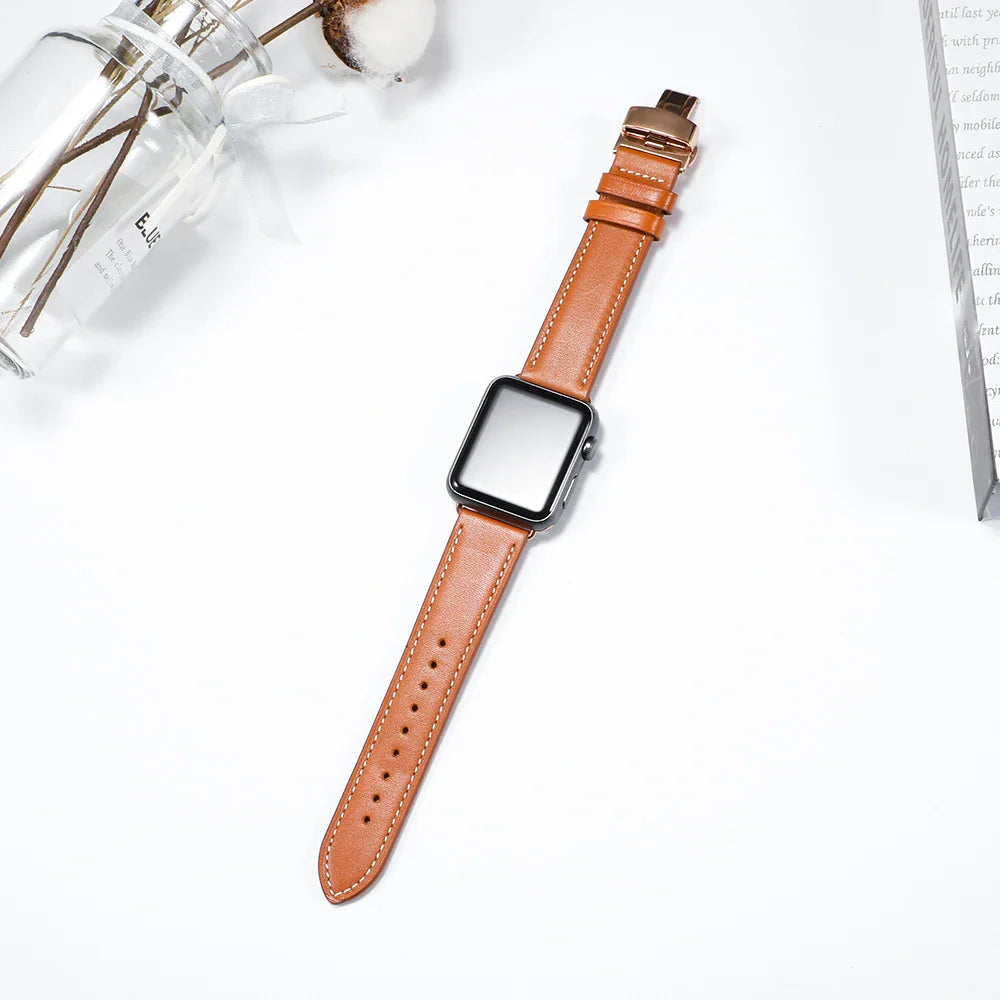 Brown leather watch band laid out on a white surface