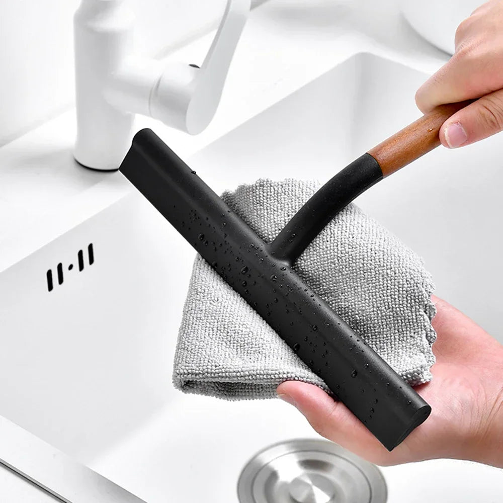 Hand holding a black silicone window wiper with a wet cleaning cloth