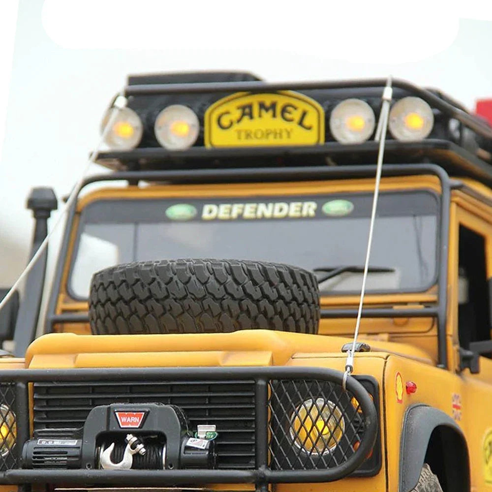 Close-up front view of a yellow remote control off-road truck featuring roof lights and installed limb riser cables