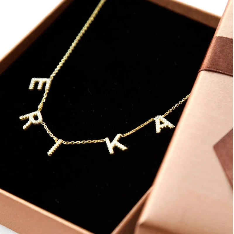 Gold letter necklace with crystals inside a brown gift box
