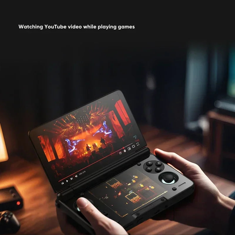 A person holding an open dual screen clamshell game console showing a video playing on the top screen