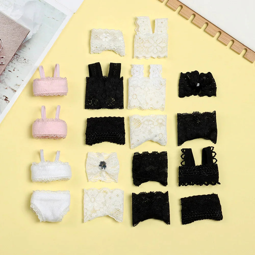 Assortment of doll lace lingerie sets and accessories displayed on a yellow surface.