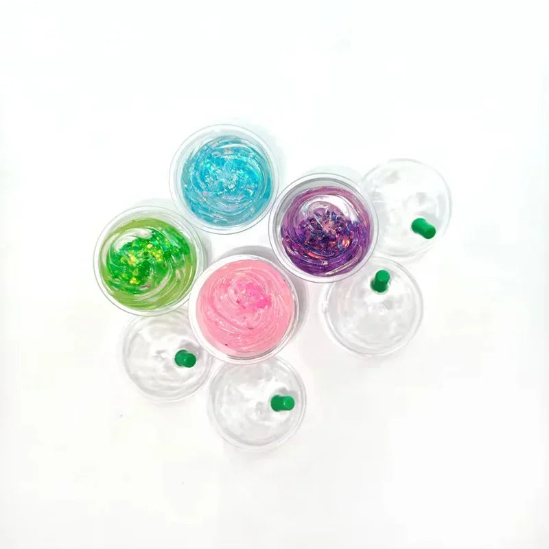 Top-down view of several small, glittery, coffee cup shaped squishy fidget toys on a white background.