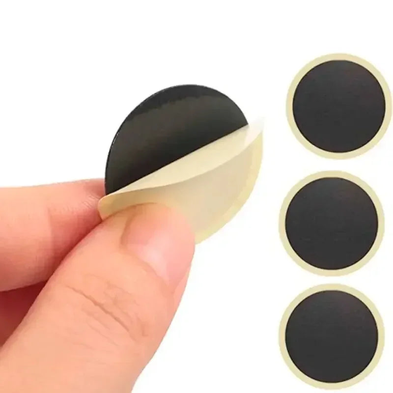 Self-adhesive black circular rubber patch with a yellow backing being peeled for bike repair.