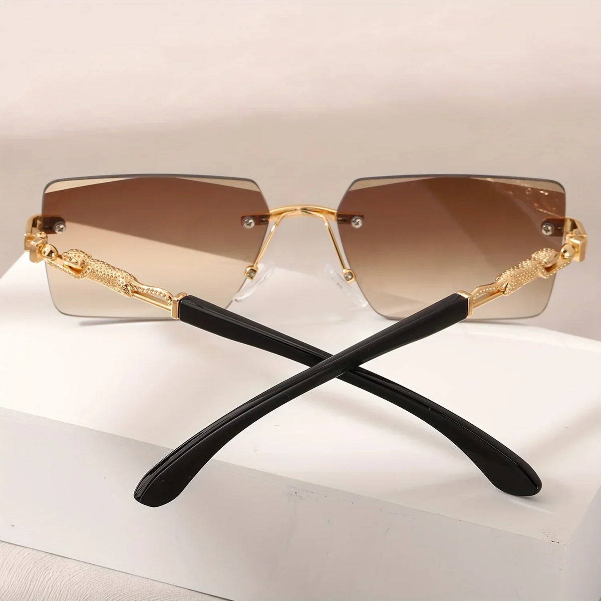Rimless rectangular sunglasses with brown gradient lenses and gold panther-style metal temples