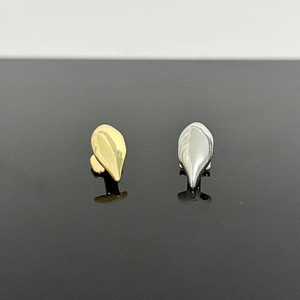A gold and a silver single vampire fang tooth cap on a black surface