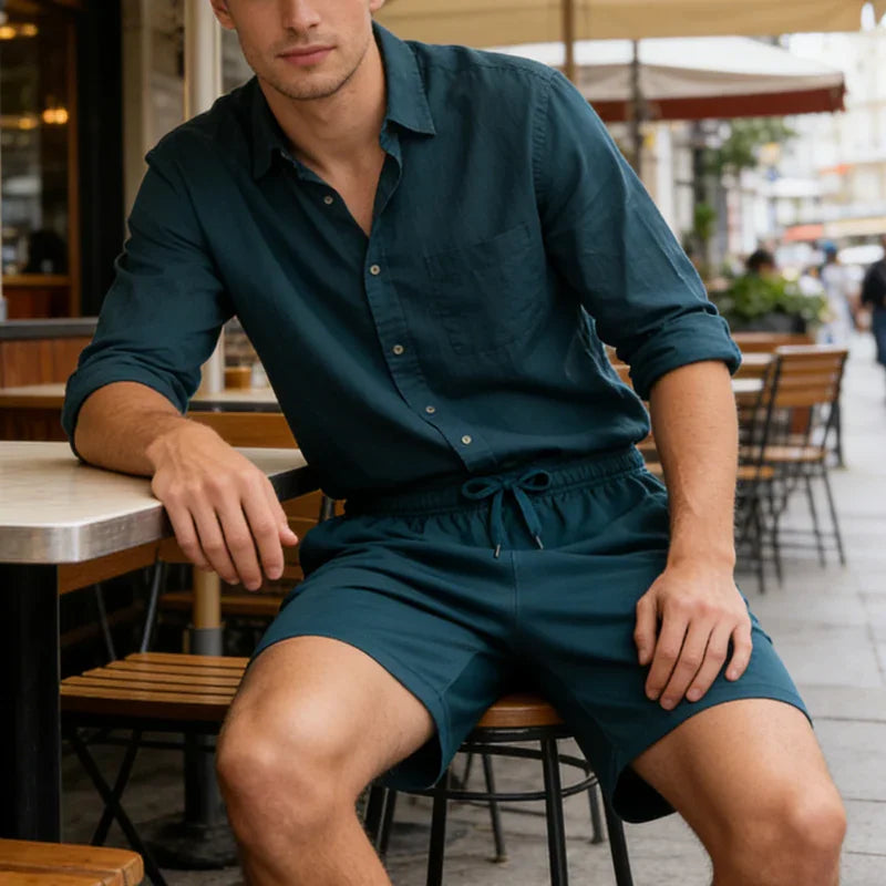 Man wearing a dark teal linen shirt and matching drawstring shorts at a table