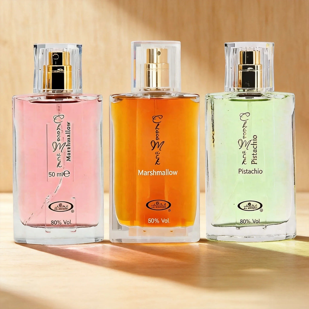 Three 50ml perfume bottles in pink, orange, and light green standing on a wooden surface in warm sunlight.