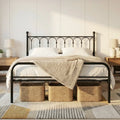 Black metal platform bed frame in a styled bedroom with under-bed storage baskets