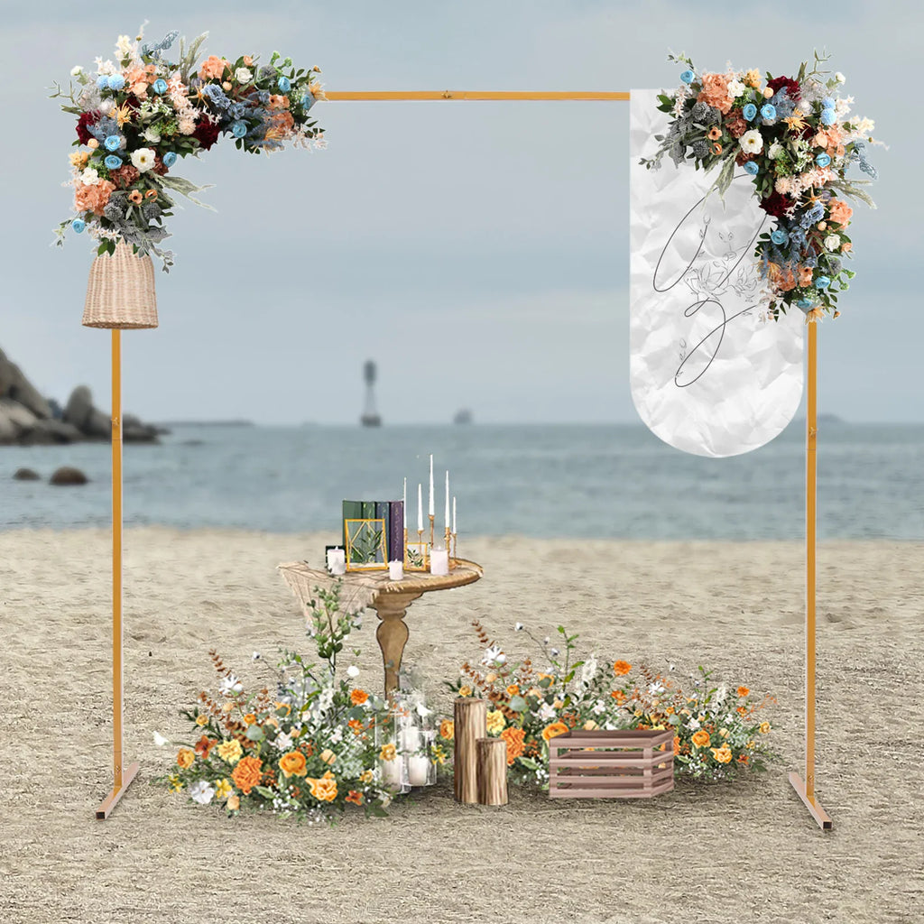Golden square arch stand with flowers and a wedding table setup on a beach