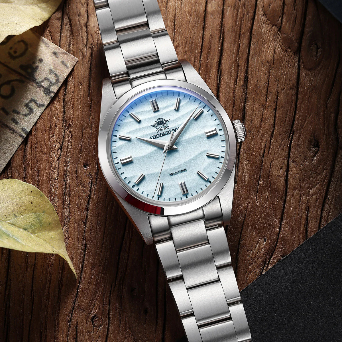 Stainless steel wristwatch with a light blue wave-patterned dial on a wooden table