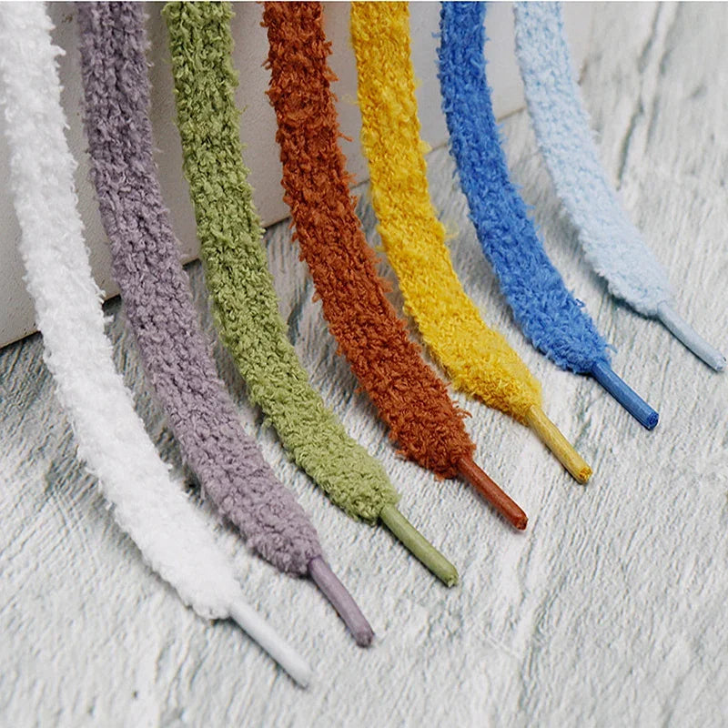A set of fluffy, multi-coloured plush shoelaces in white, purple, green, brown, yellow, and blue.