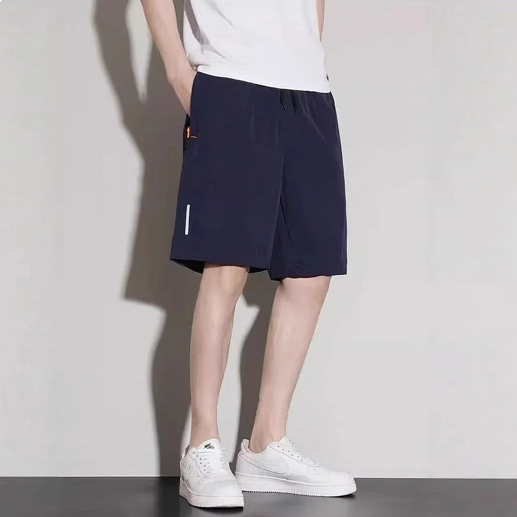 Man wearing navy blue athletic shorts with side zipper pockets and reflective trim, paired with a white t-shirt